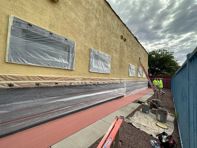 Exterior stucco wall being prepped and painted